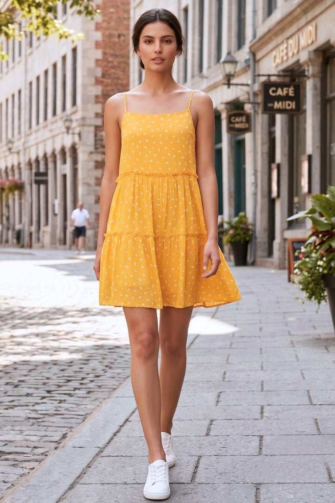 Sunshine yellow ditsy print spaghetti strap tiered mini dress - front view on cobblestone street