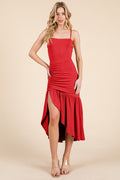 Black square-neck spaghetti-strap side-ruched high-low ruffle-hem midi dress with side slit - close-up skirt detail showing dense side ruching at hip, thigh-high front slit, and wide gathered ruffle hem in black