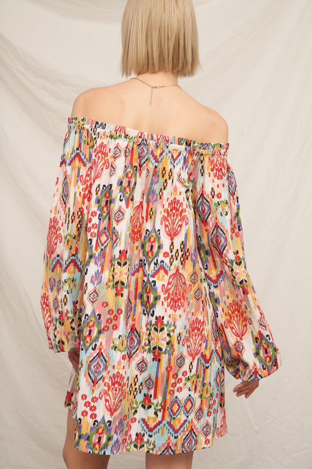 Multicolour ikat print off-shoulder long bishop-sleeve babydoll mini dress - back view showing off-shoulder line and full bishop sleeves