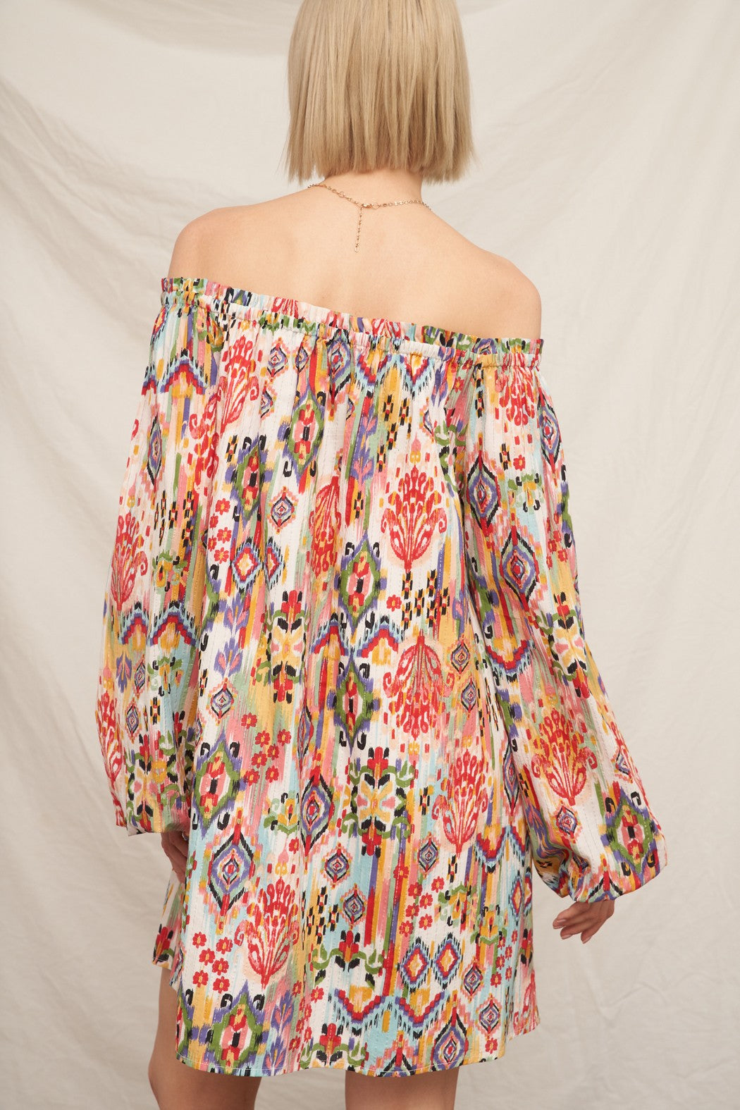 Multicolour ikat print off-shoulder long bishop-sleeve babydoll mini dress - back view showing off-shoulder line and full bishop sleeves