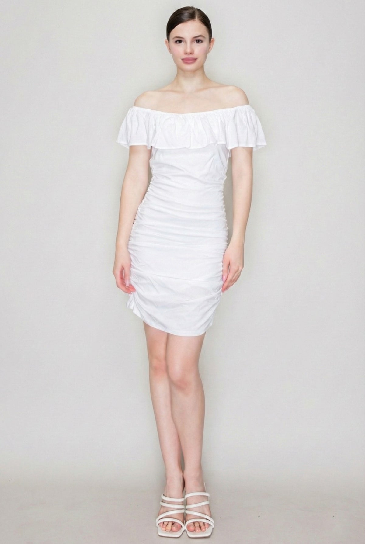 White off-shoulder ruffle-collar allover-ruched bodycon mini dress - front full view showing wide off-shoulder ruffle collar, smooth bodice, fully ruched bodycon skirt, and mini hem