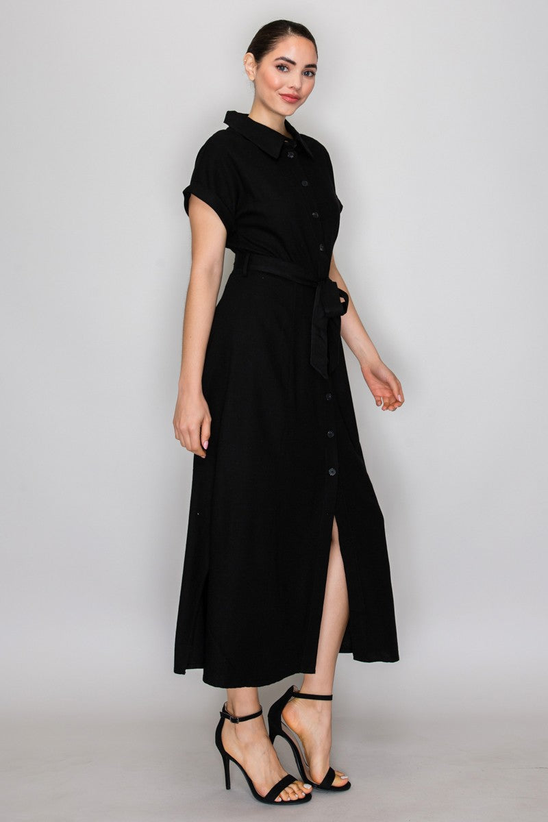 Black short-sleeve shirt-collar button-front belted side-slit maxi dress - side three-quarter view showing pointed collar, short sleeves, button placket, self-tie belt, gently A-line maxi skirt silhouette, and side slit at hem