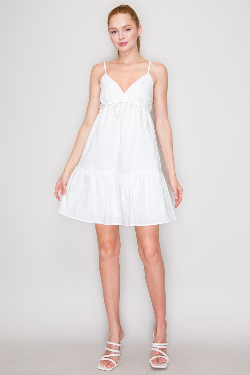 White Swiss dot V-neck bow-front empire-waist tiered babydoll mini dress - second front full view showing complete silhouette, V-neck gathered bust with bow, double spaghetti straps, full tiered babydoll mini, and ruffle hem in white
