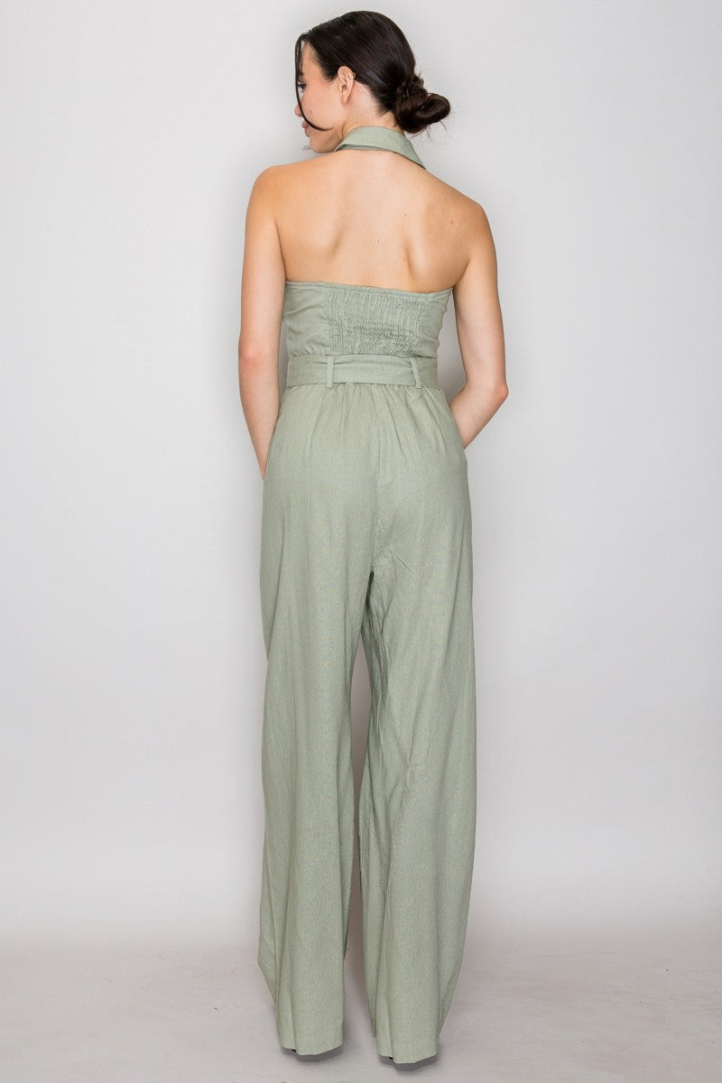 Blush pink halter-collar button-front belted wide-leg jumpsuit - side three-quarter view showing open collar, halter construction, button front bodice, square-buckle self-fabric belt, and full-length wide-leg trousers in blush pink