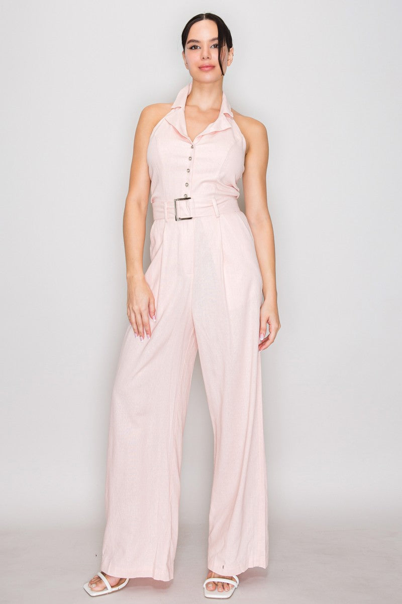 Natural linen halter-collar button-front belted wide-leg jumpsuit - close-up bodice detail showing open pointed shirt collar, centre-front gold-tone metallic buttons, and bold square gold-buckle self-fabric belt at natural waist in natural linen
