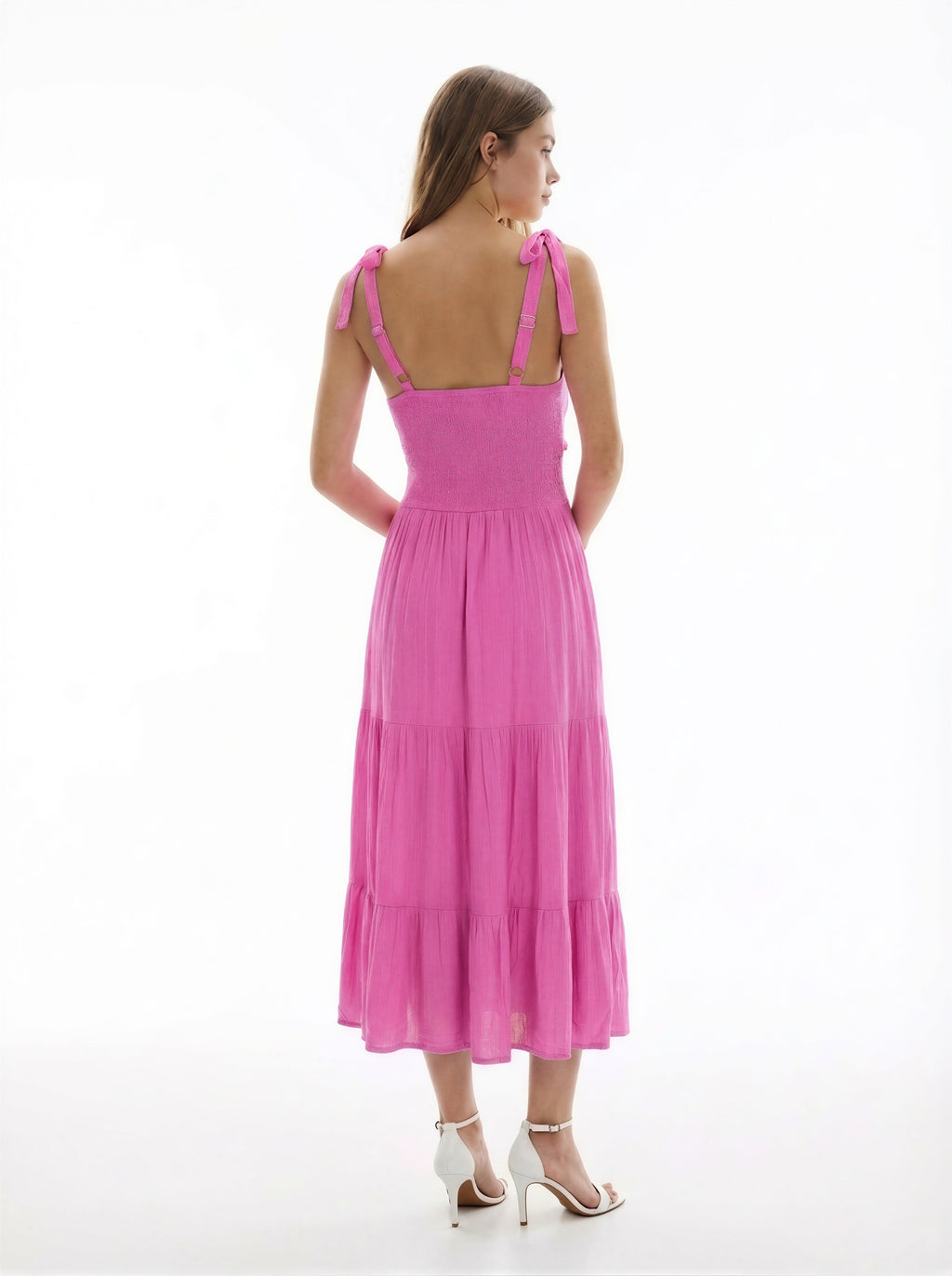 Hot pink V-neck tie-shoulder smocked-waist tiered midi dress - close-up back detail showing gold hardware at strap connection, tie-bow shoulder straps, and dense smocked back bodice rows in vibrant hot pink