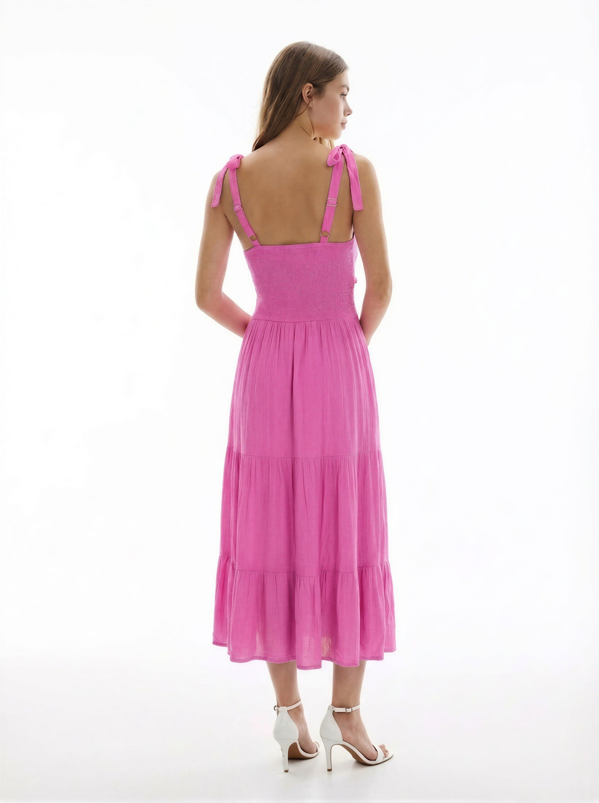 Hot pink V-neck tie-shoulder smocked-waist tiered midi dress - close-up back detail showing gold hardware at strap connection, tie-bow shoulder straps, and dense smocked back bodice rows in vibrant hot pink