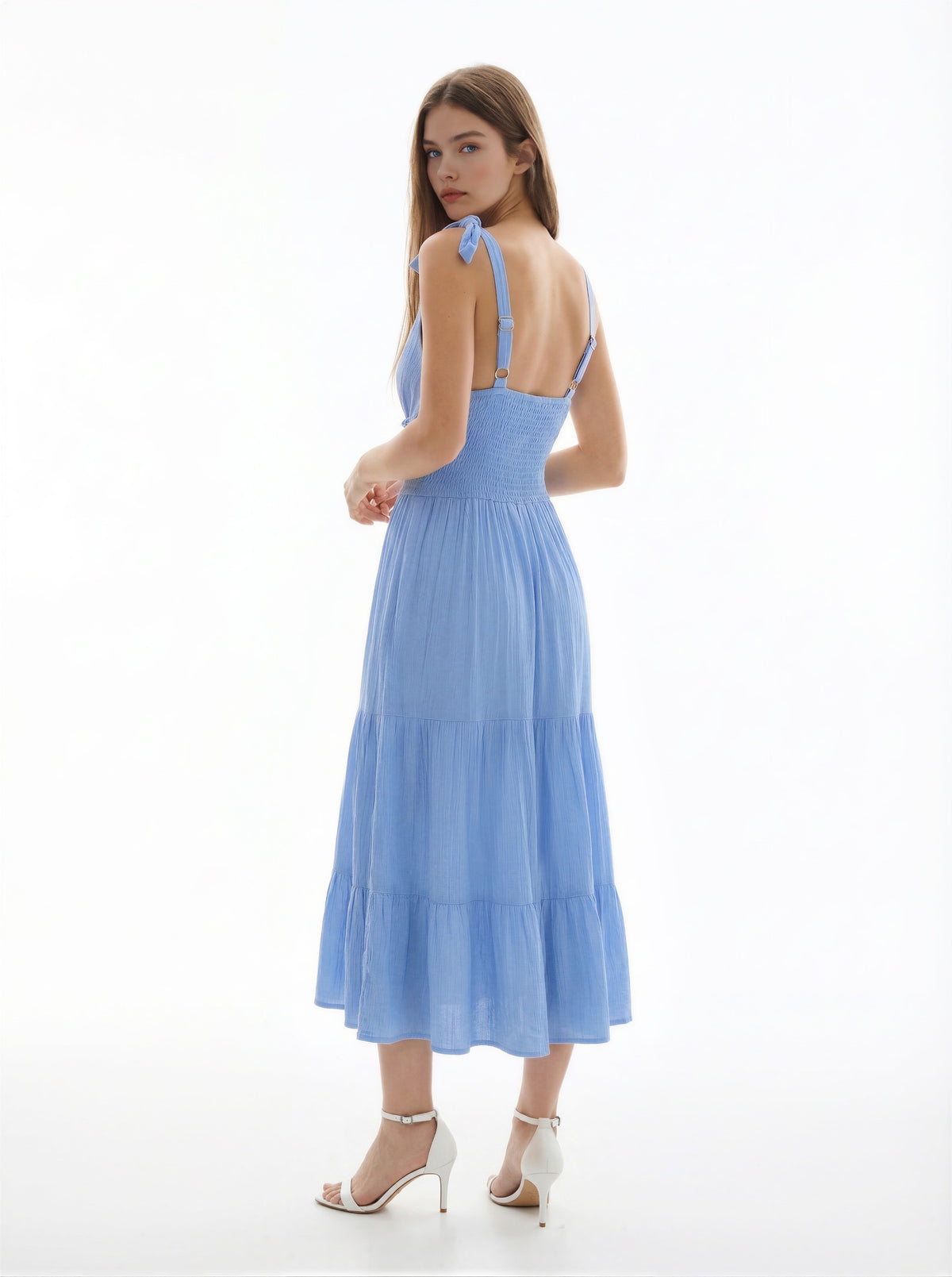 White V-neck tie-shoulder smocked-waist tiered midi dress - back three-quarter view showing tie-bow shoulder straps at back, open back smocked bodice, and full tiered skirt from behind in white