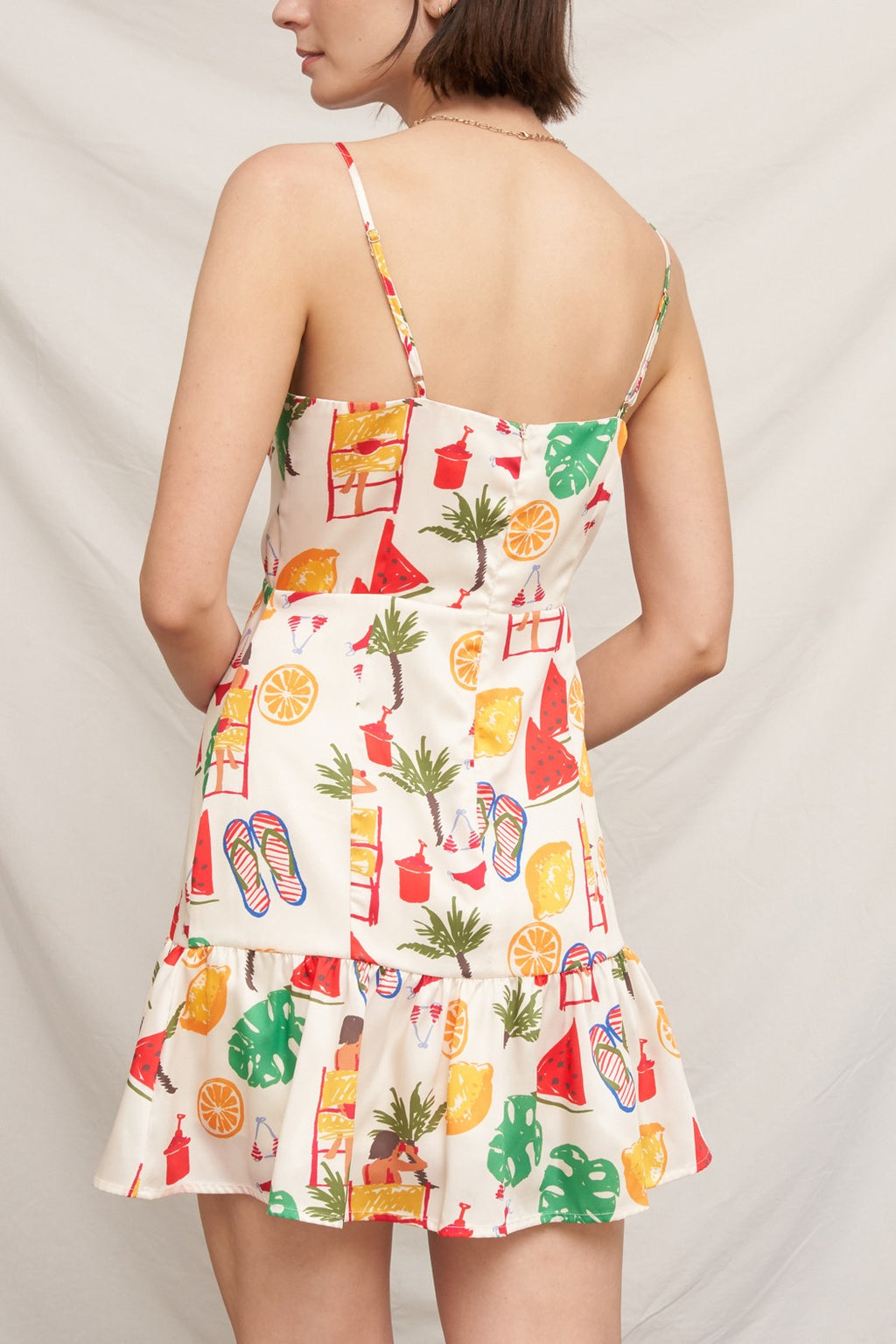 Tropical beach novelty-print spaghetti-strap square-neck fitted-bodice tiered-ruffle-hem mini dress - front close-up showing watermelon, orange, monstera, flip flop, and beach print on fitted bodice