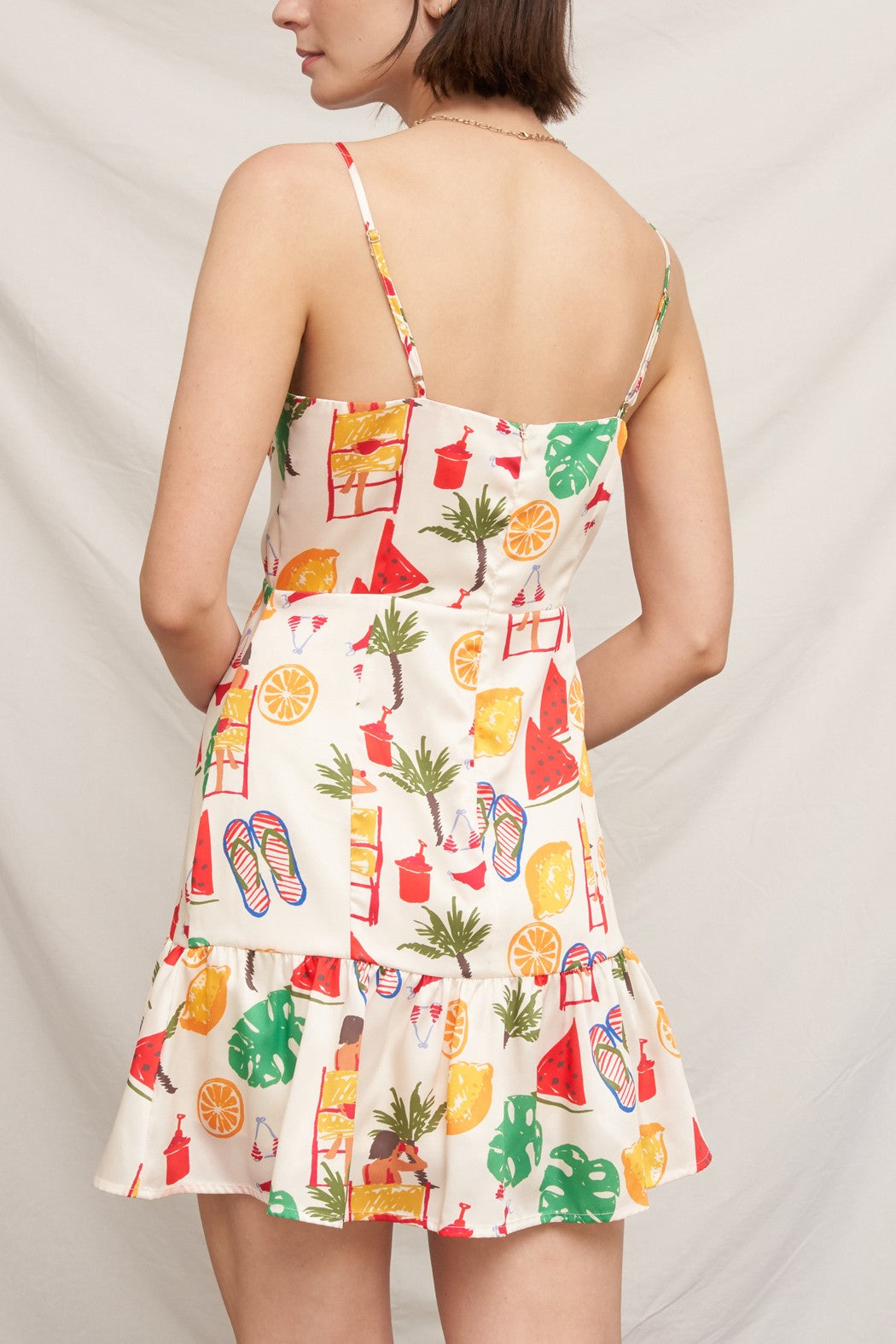 Tropical beach novelty-print spaghetti-strap square-neck fitted-bodice tiered-ruffle-hem mini dress - front close-up showing watermelon, orange, monstera, flip flop, and beach print on fitted bodice