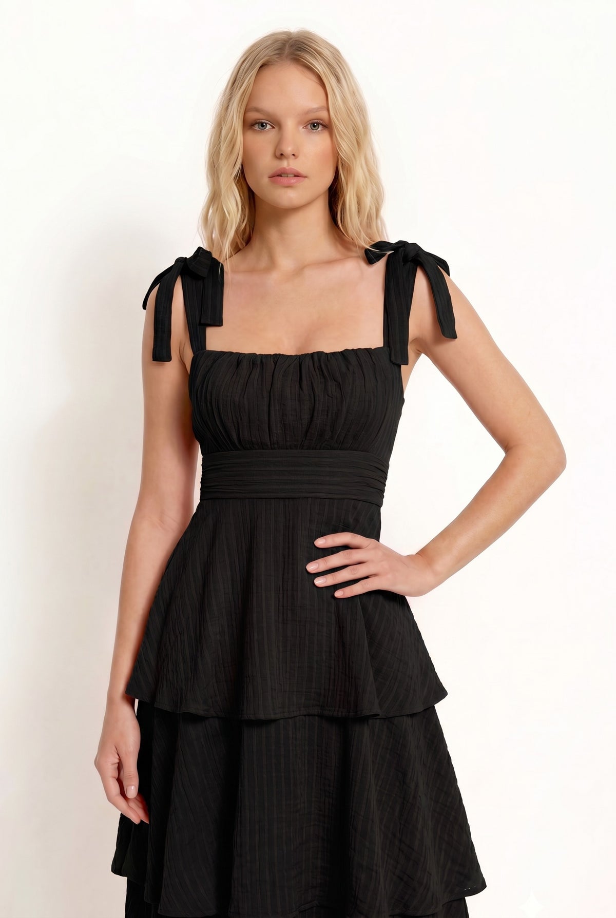 Black shoulder-tie-strap ruched-bust smocked-waist three-tier midi dress - alternate front three-quarter view showing shoulder tie bows, ruched bust, smocked waistband, and full three-tier cascading midi skirt in deep black crinkle fabric