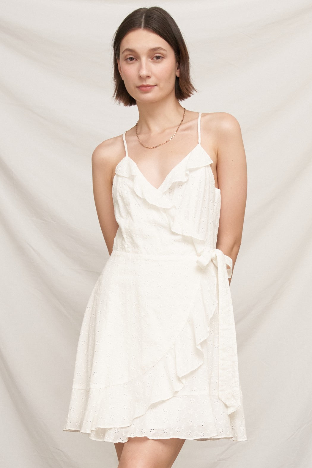 White eyelet spaghetti-strap V-neck ruffle-wrap tie-waist mini dress - second front full view showing V-neck ruffle wrap, tie waist, gently flared eyelet mini, and broderie anglaise hem frill