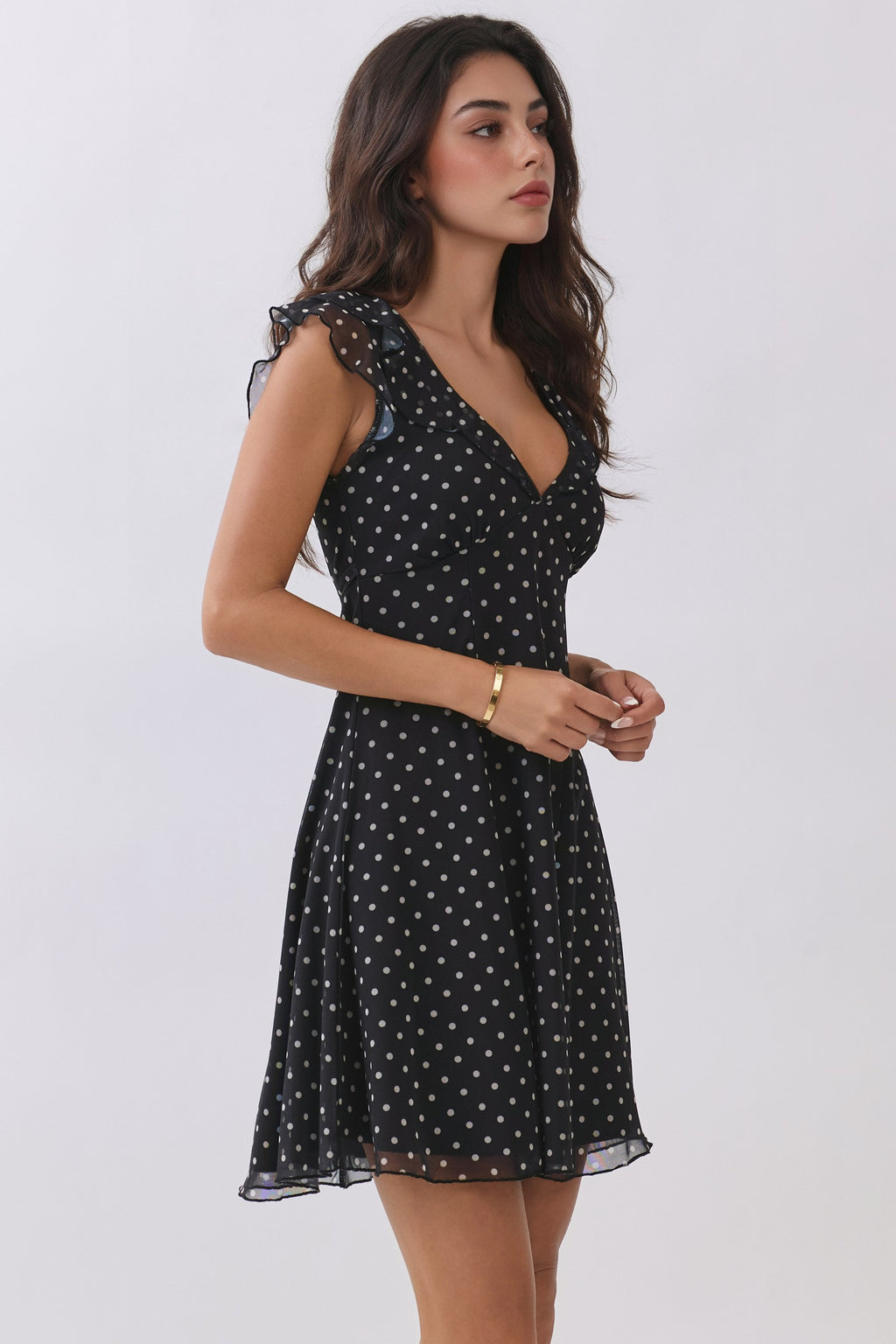Black polka-dot chiffon deep-V ruffle-sleeve back-tie fit-and-flare mini dress - side view showing ruffle cap sleeve, fitted bodice, and flared mini skirt