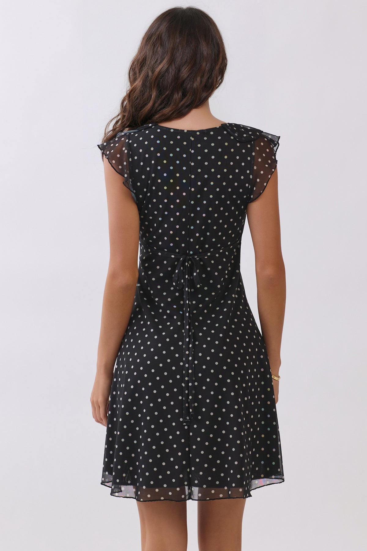 Black polka-dot chiffon deep-V ruffle-sleeve back-tie fit-and-flare mini dress - back view showing open V back neckline, centre-back self-tie bow, and ruffle sleeves