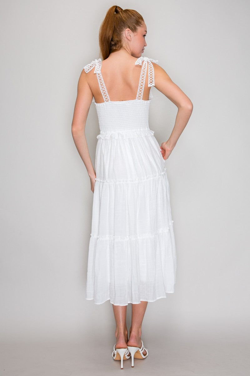 White square-neck smocked-bodice crochet-lace-strap tie-bow tiered midi dress - back full view showing wide crochet lace straps with bow ties at each shoulder, open smocked back bodice, and full tiered midi skirt from behind in crisp white