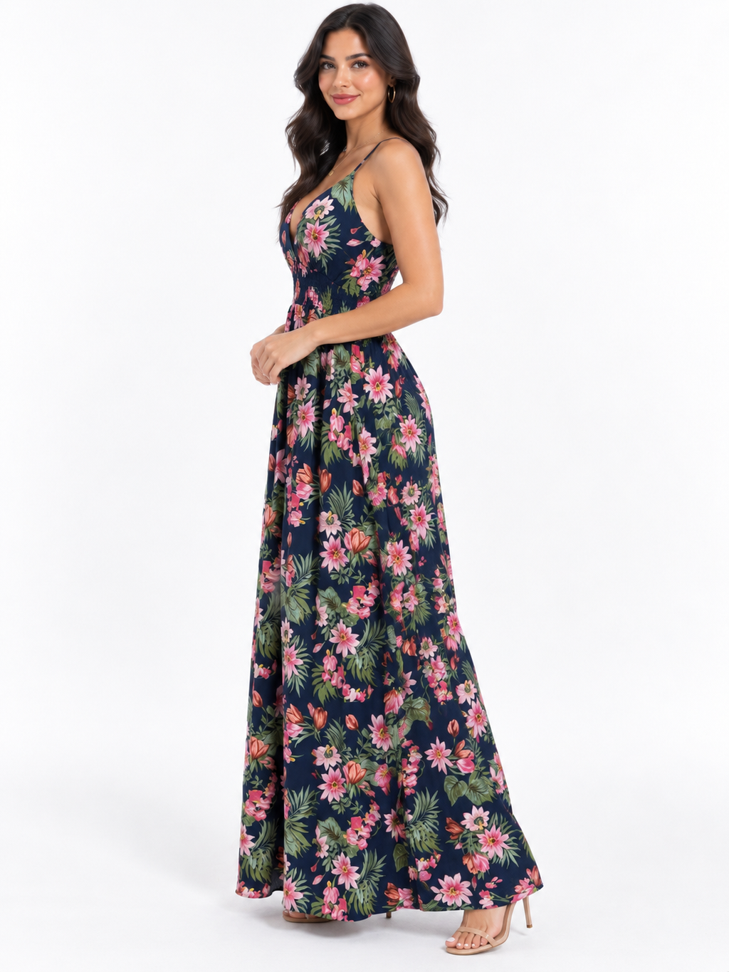 Navy tropical-floral spaghetti-strap deep-V crossback smocked-waist flowy maxi dress - side three-quarter white background view showing fine spaghetti straps, deep-V neckline profile, smocked waistband, and voluminous flowy maxi skirt from the side in deep navy tropical floral print with heels