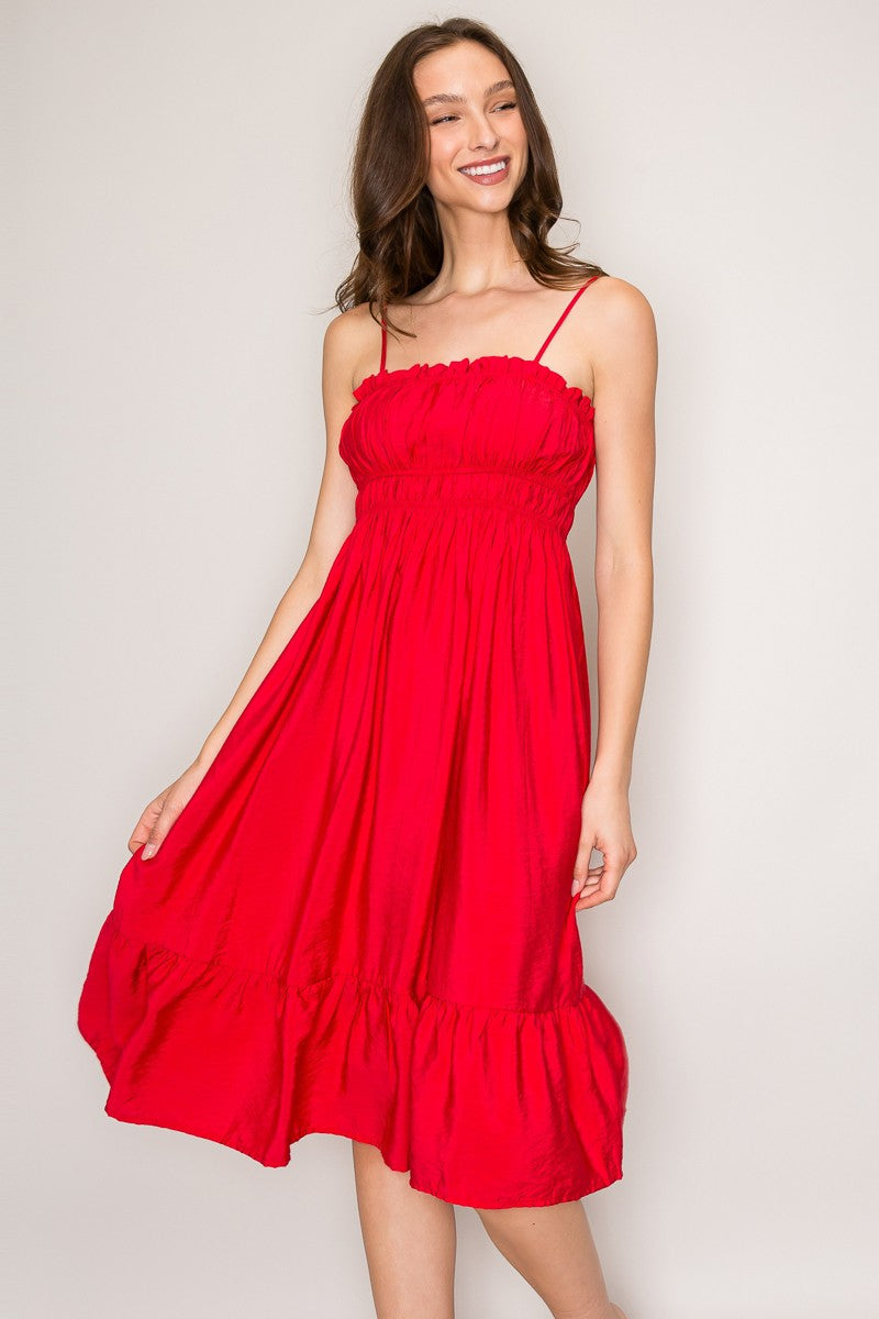 Red spaghetti-strap ruffle-trim smocked-bodice tiered midi dress - side three-quarter view showing spaghetti straps, smocked bodice profile, and full tiered A-line midi skirt silhouette from the side in bold red