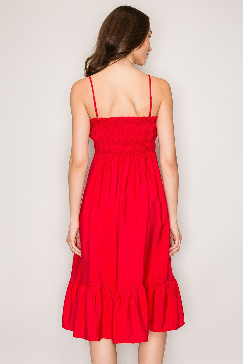 Red spaghetti-strap ruffle-trim smocked-bodice tiered midi dress - front three-quarter view showing spaghetti straps, ruffle trim neckline, smocked bodice, and flowing tiered midi skirt in motion in bold red