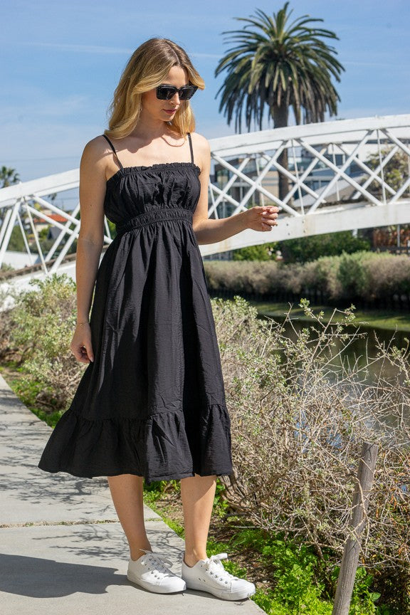 Black spaghetti-strap ruffle-trim smocked-bodice tiered midi dress - front three-quarter view showing fine spaghetti straps, delicate ruffle neckline trim, fully smocked bodice, and full tiered A-line midi skirt in deep black