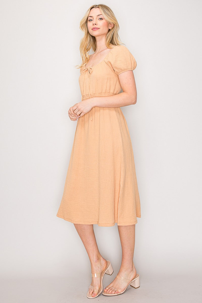 Peach crinkle-woven sweetheart-neck front-tie puff-sleeve smocked-waist fit-and-flare midi dress - three-quarter side view showing puff sleeves, smocked waist, and midi length
