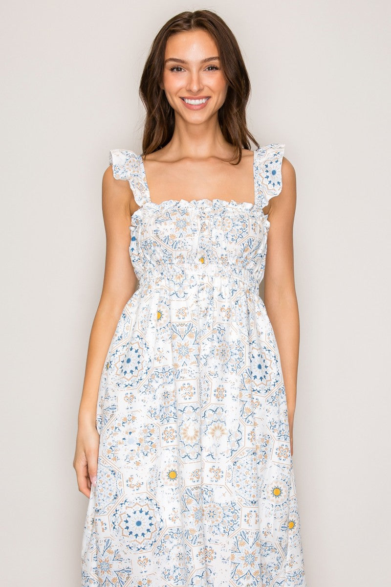 White botanical tile-print square-neck ruffle-strap smocked-bodice tiered midi dress - close-up upper bodice and strap detail showing ruffle-frill neckline trim, wide ruffle-edged strap, and smocked bodice in intricate botanical tile print with dusty blue, gold, blush, and sage on white