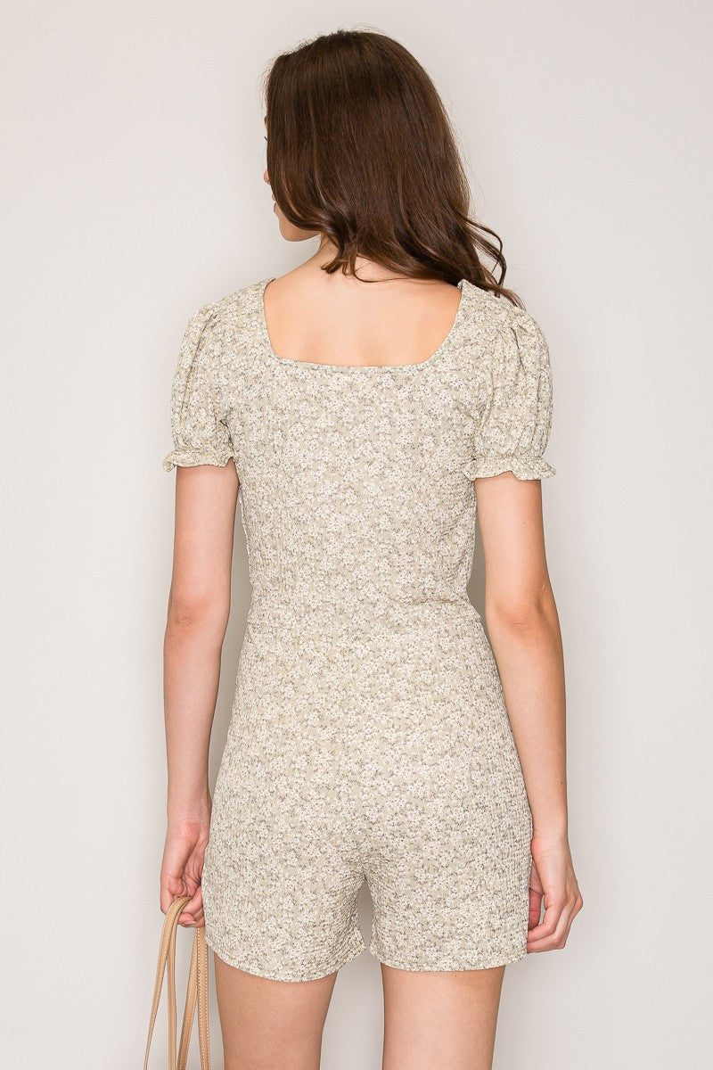 Cream ditsy-floral deep-V surplice puff-sleeve lettuce-edge smocked-waist short romper - back view showing wide square back neckline, puff sleeves, and smocked waistband