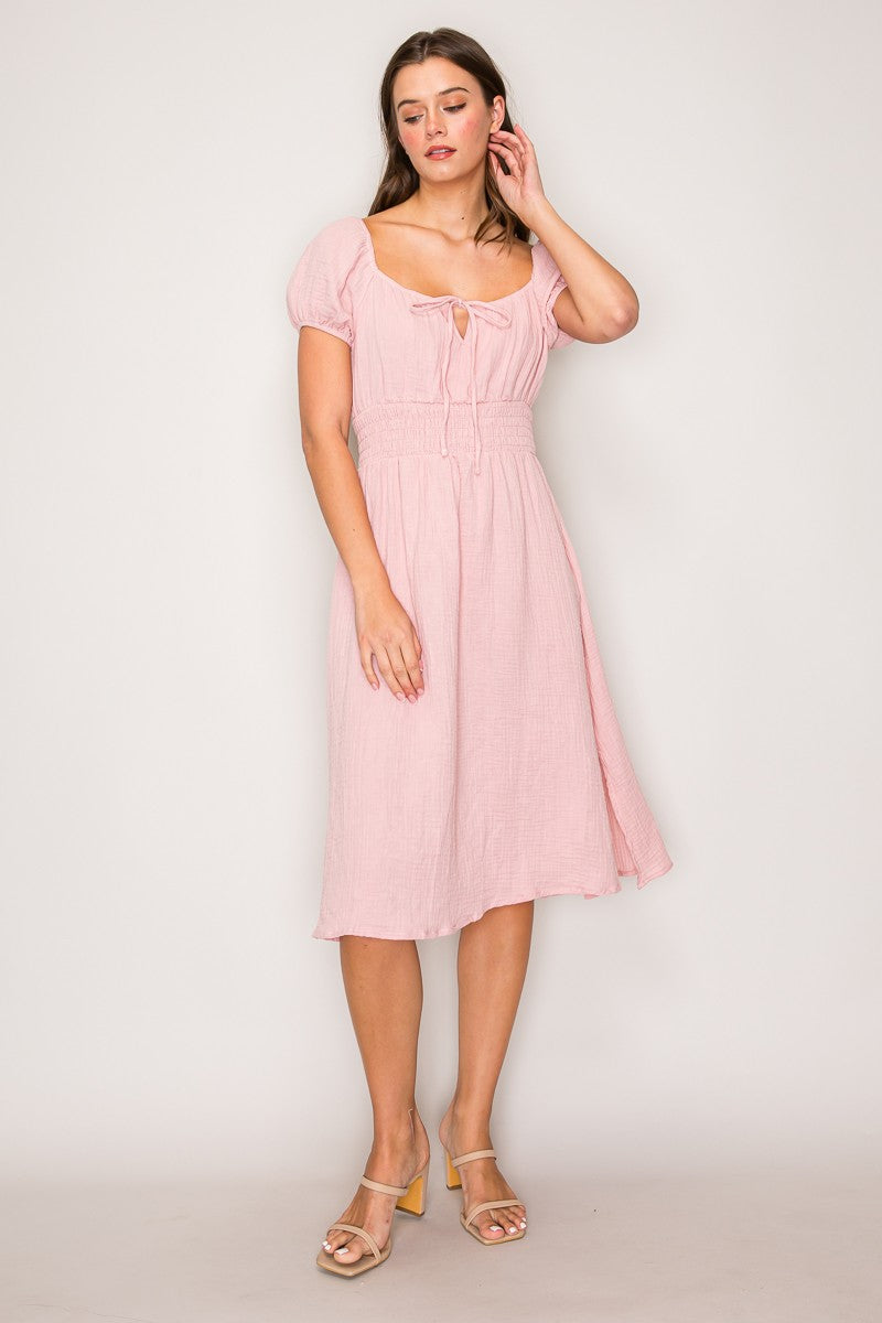 Blush pink crinkle-woven sweetheart-neck front-tie puff-sleeve smocked-waist fit-and-flare midi dress - three-quarter front view showing puff sleeves, smocked waist, and full skirt